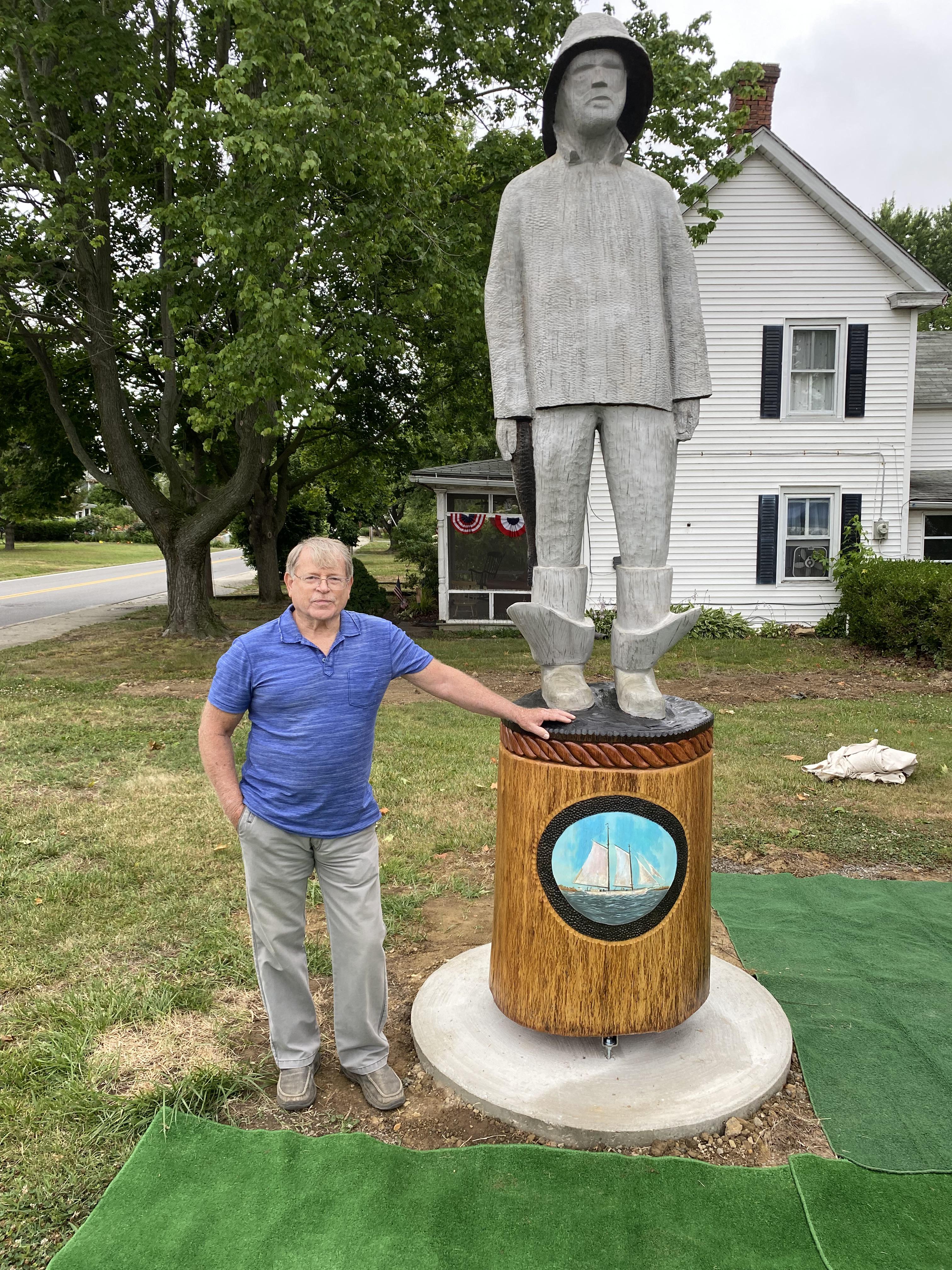 The restoration artist John Elburn proudly stands next to the restored Old Salt sculpture